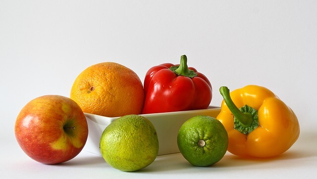 Kolorowe owoce i warzywa z białą salaterką, na białym tle