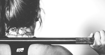 Oferta klubów fitness to nie tylko siłownia! Wysportowana kobieta z drązkiem do podnoszenia ciężarów