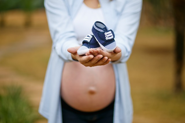 Kobieta w ciąży trzyma bucik