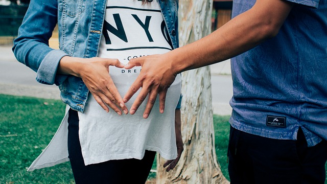 Szczęśliwa para robi znak serca na brzuchu kobiety w ciąży