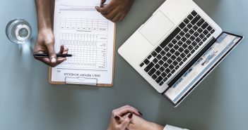 Jakie kwalifikacje powinna mieć opiekunka osób starszych? Laptop i dokumenty na stole