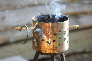 Dymiąca metalowa kadzidelnica na drewnianym tarasie wydzielająca dym odstraszający owady