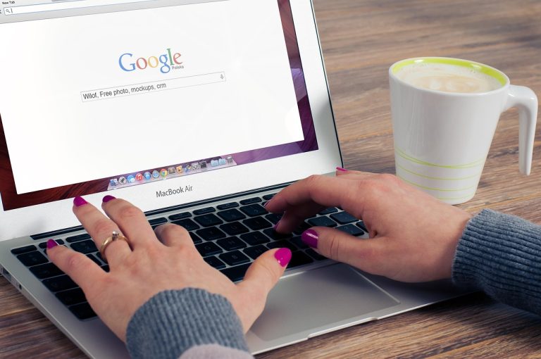 Dłonie piszące na klawiaturze laptopa z otwartą wyszukiwarką Google